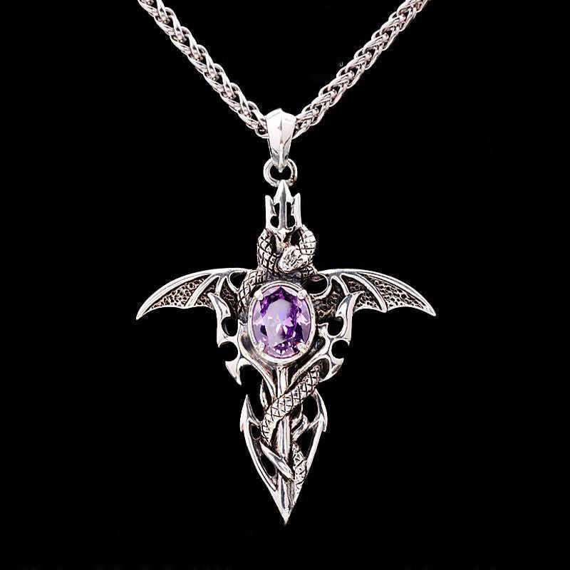 Dragon bat wing pendant necklace with purple amethyst gemstone displayed in open black velvet gift box, styled in candlelit gothic interior with ornate gold frame in background — Shadow Realm Supply