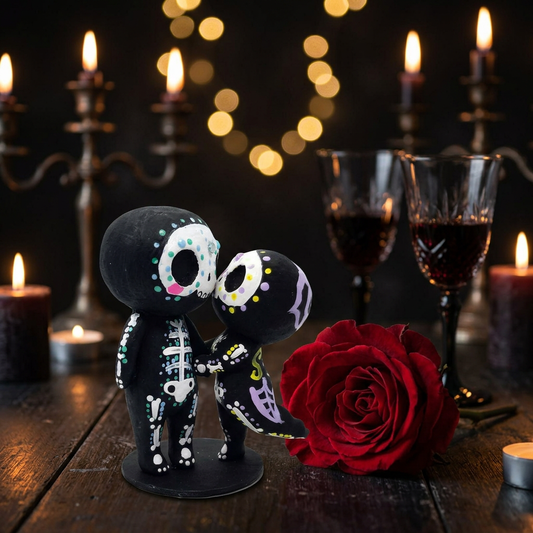 Day of the Dead skeleton couple figurines kissing next to a red rose, warm candlelight bokeh background, gothic romantic home decor