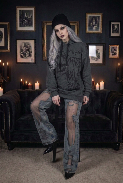 Goth model with silver-gray hair wearing oversized dark gray gothic drip graphic hoodie with black beanie and heavily destroyed mesh fishnet flare jeans with stiletto heels, front view in candlelit gothic interior — dark aesthetic alt grunge streetwear outfit — Shadow Realm Supply