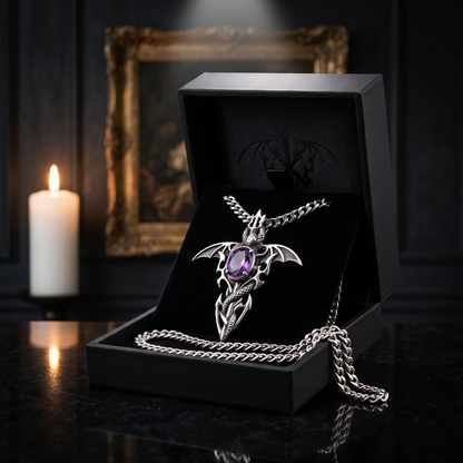 Dragon bat wing pendant necklace with purple amethyst gemstone displayed in open black velvet gift box, styled in candlelit gothic interior with ornate gold frame in background — Shadow Realm Supply